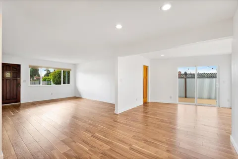 a view of an empty room with window and wooden floor