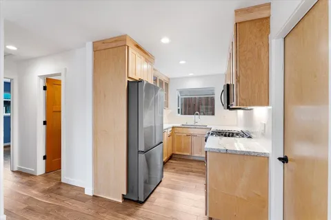 a kitchen with stainless steel appliances granite countertop a refrigerator a stove and a sink