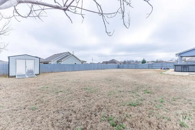 a view of a dry yard with wooden fence