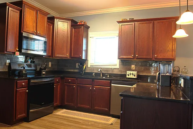 a kitchen with stainless steel appliances granite countertop a sink a stove counter space and cabinets