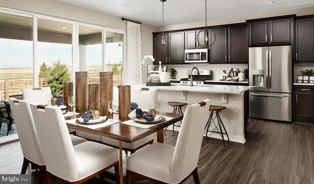 a kitchen with stainless steel appliances granite countertop a dining table chairs refrigerator and sink