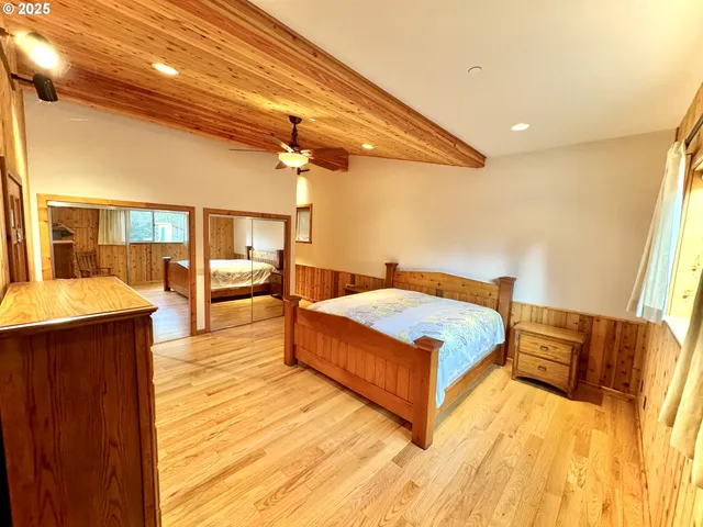 a spacious bedroom with a bed and wooden floor