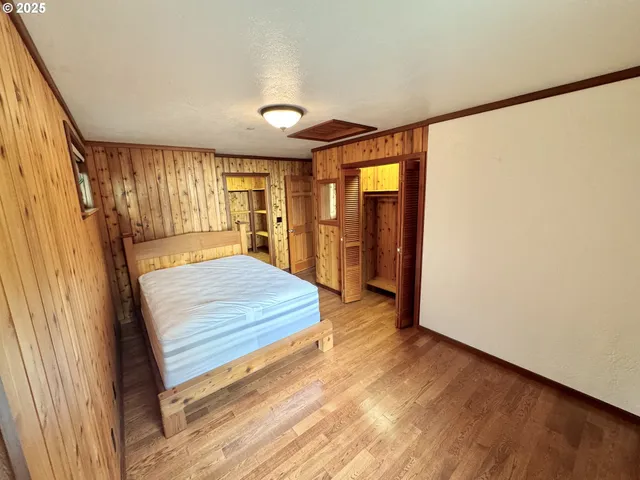 a spacious bedroom with a bed and wooden floor