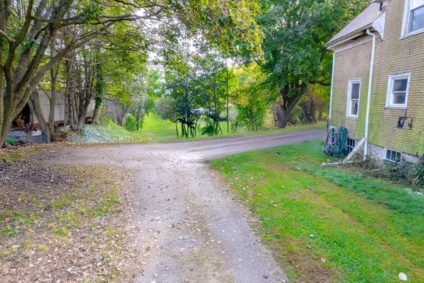 a view of a house with a small yard plants and wooden fence