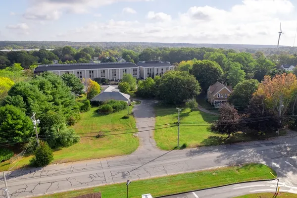 a view of a yard in front of a brick house with large windows