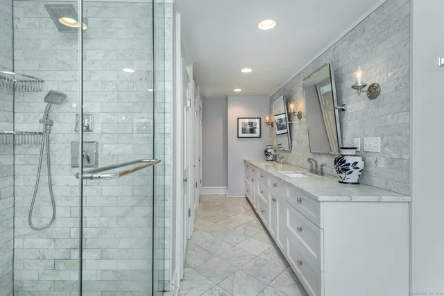 a bathroom with a double vanity sink a large mirror a shower and