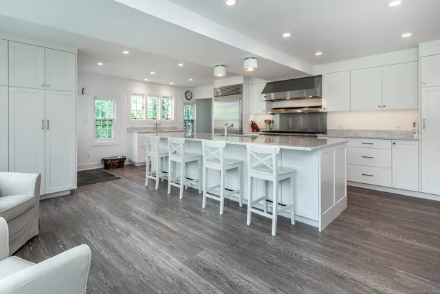a kitchen with stainless steel appliances kitchen island granite countertop a table chairs sink and cabinets