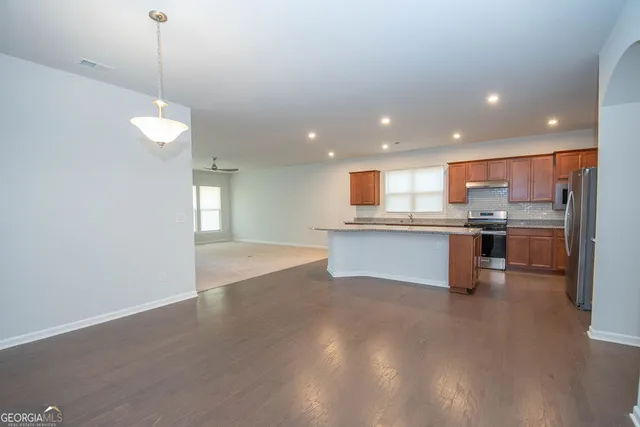 a kitchen with stainless steel appliances granite countertop wooden cabinets a sink a stove a kitchen island and a window