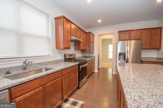 a kitchen with stainless steel appliances granite countertop a refrigerator and a sink