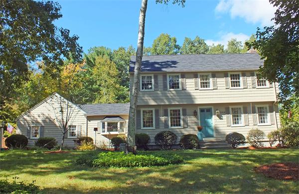 a front view of a house with a garden and trees