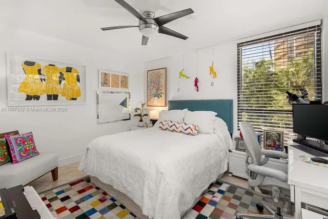 a bedroom with a bed a computer on the desk and a book shelf