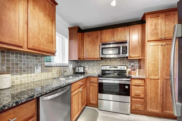 a kitchen with granite countertop wooden cabinets and stainless steel appliances