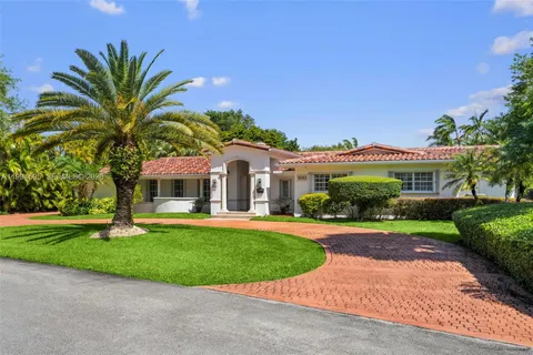 a view of a white house with a big yard and potted plants