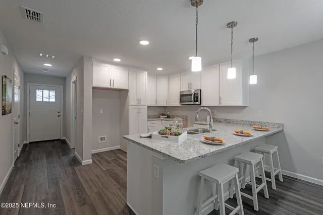 a kitchen with stainless steel appliances granite countertop a refrigerator a sink a stove a dining table and chairs with wooden floor