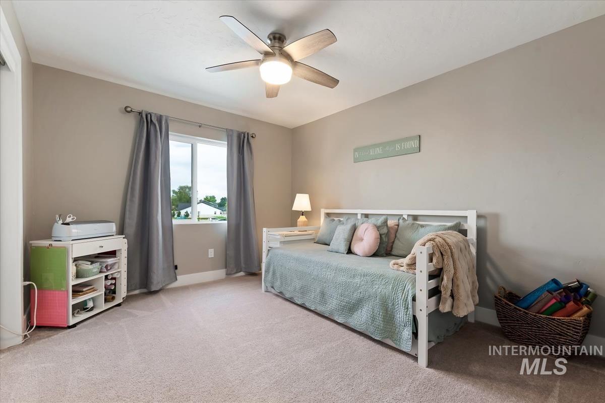815 Knowledge Street Middleton, ID 83644 - Photo 34 of 49 Neutral tone walls with crown molding, light-colored carpeting, a window with gray drapes, and a ceiling fan with integrated lighting