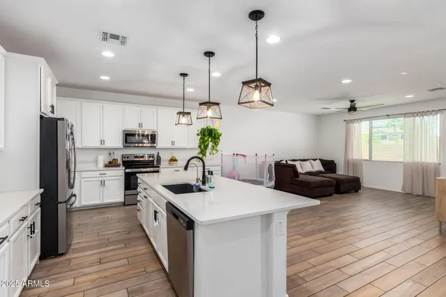 a kitchen with counter top space a sink stainless steel appliances and wooden floor