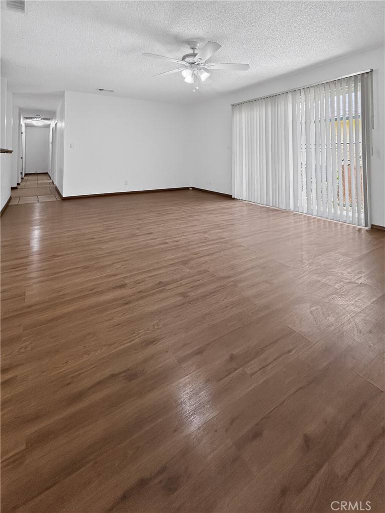 7451 Diamond Street Riverside, CA 92504 - Photo 9 of 31 an empty room with wooden floor ceiling fan and windows