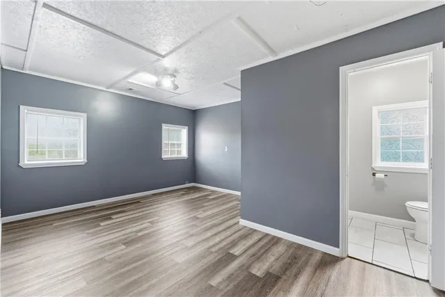 a view of an empty room with window and wooden floor