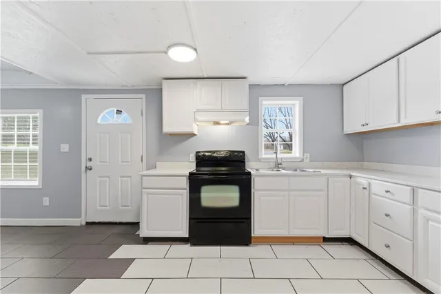 a kitchen with white cabinets a stove and a window