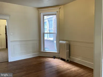 an empty room with wooden floor cabinet and windows