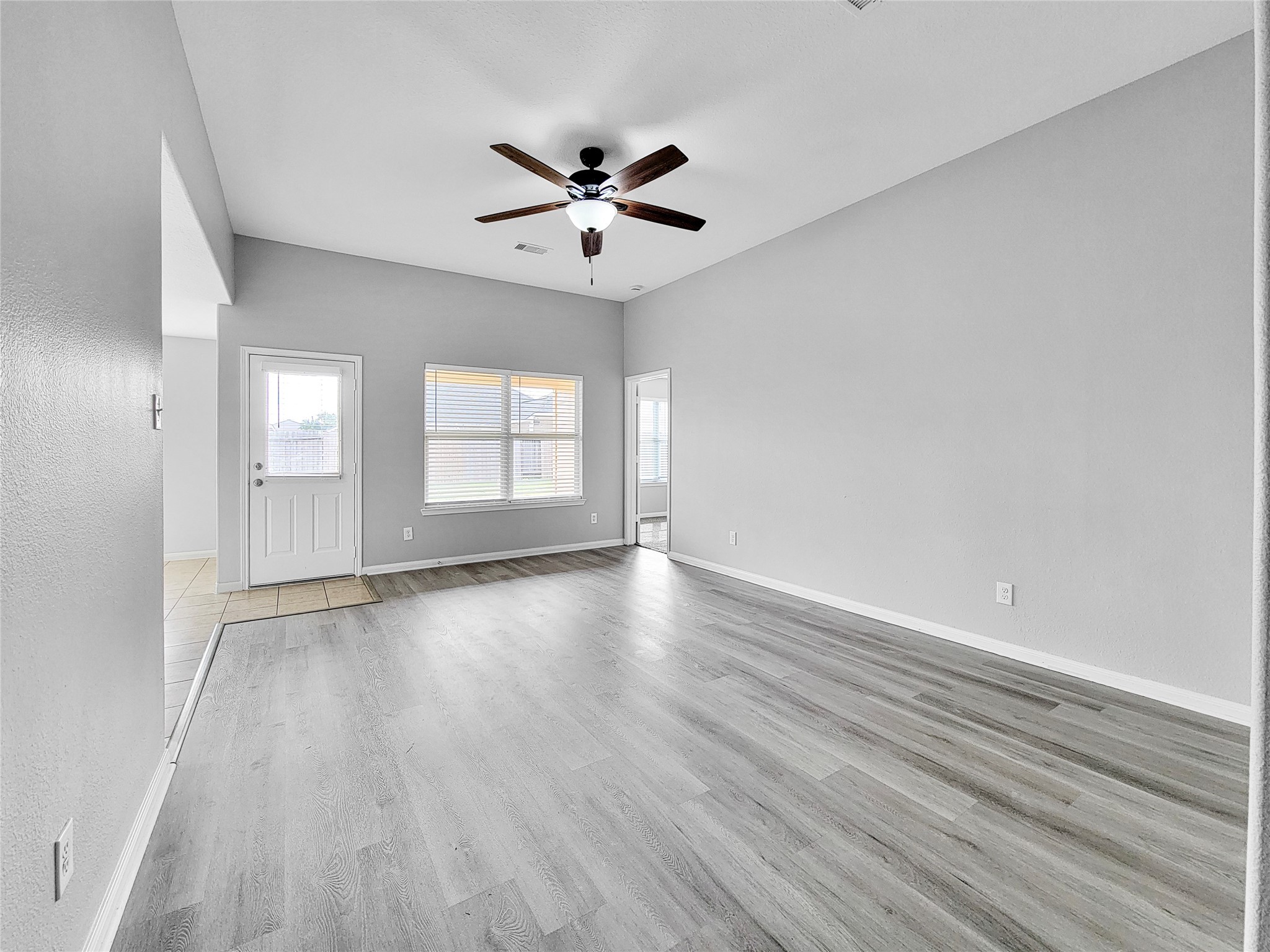 930 Paradise Road Baytown, TX 77521 - Photo 4 of 18 an empty room with wooden floor fan and windows