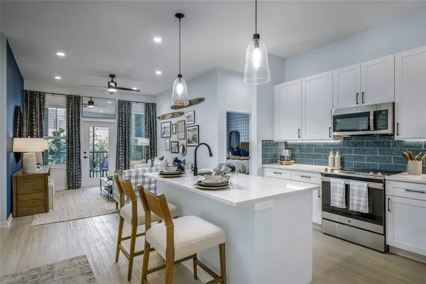 a kitchen with stainless steel appliances a refrigerator a stove a microwave oven a sink with a dining table and chairs