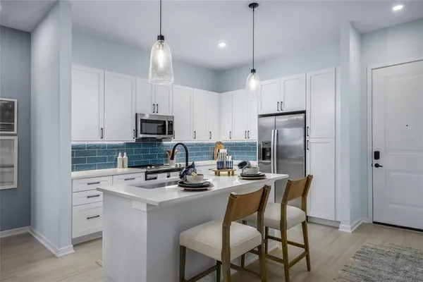 a kitchen with stainless steel appliances granite countertop a sink stove refrigerator and cabinets with wooden floor