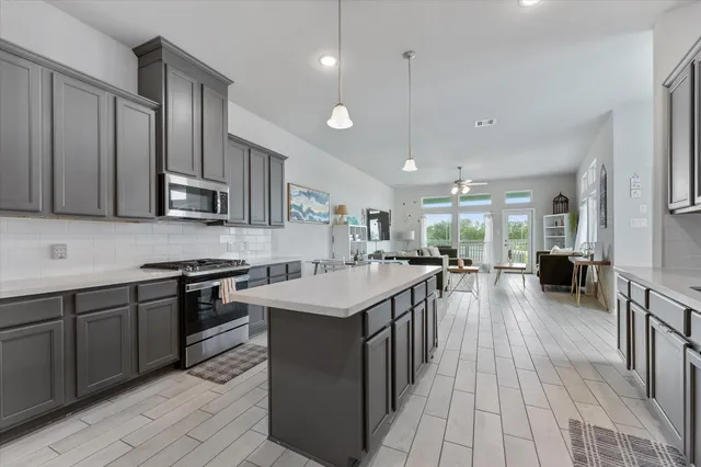 a kitchen with stainless steel appliances granite countertop a stove top oven a sink dishwasher and a refrigerator with wooden floor