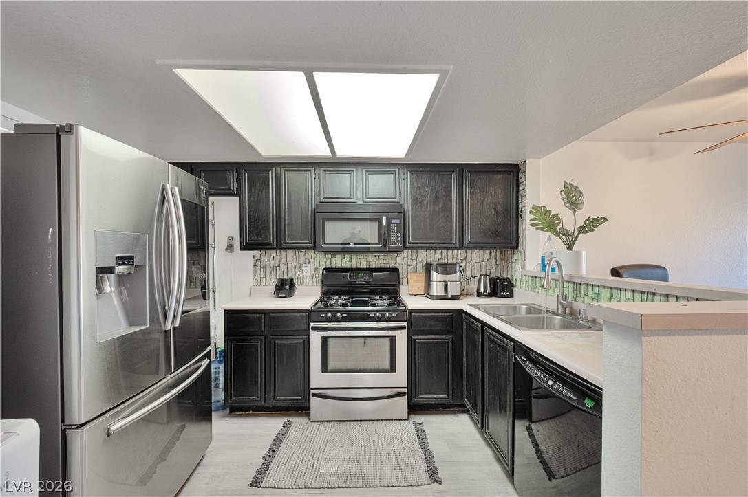 8025 West Russell Road, Unit 1090 Las Vegas, NV 89113 - Photo 3 of 23 Dark cabinetry and stainless steel appliances anchor this kitchen workspace under recessed panel lighting.