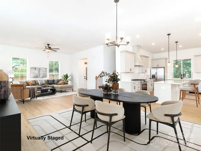 a view of a dining room and livingroom furniture wooden floor a rug and a chandelier