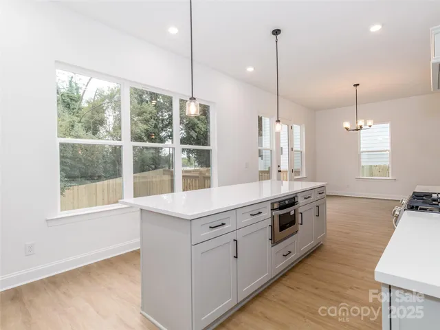 a kitchen with stainless steel appliances granite countertop a stove a sink a window and chairs