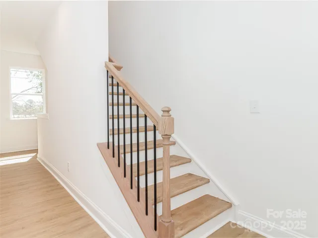a view of staircase with wooden floor and white walls