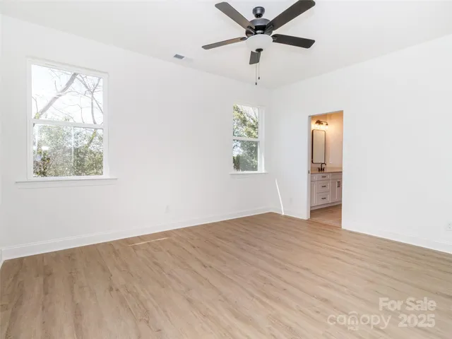 an empty room with windows and fan