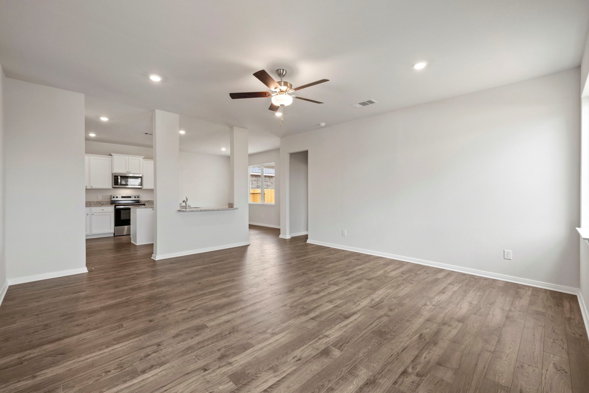 7610 Thrips Lane Richmond, TX 77469 - Photo 3 of 20 a view of an empty room with wooden floor and a kitchen
