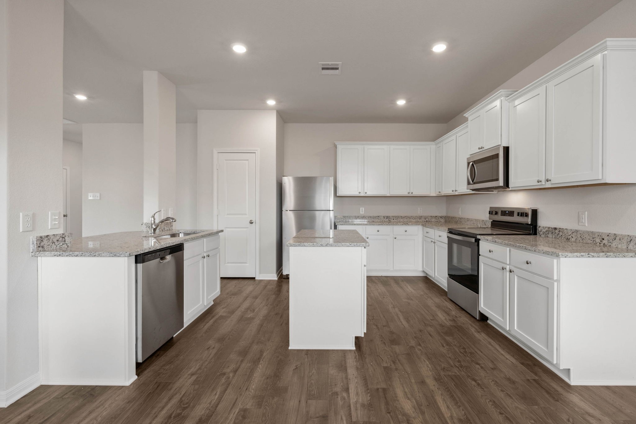 7610 Thrips Lane Richmond, TX 77469 - Photo 6 of 20 a white kitchen with wooden floor and stainless steel appliances