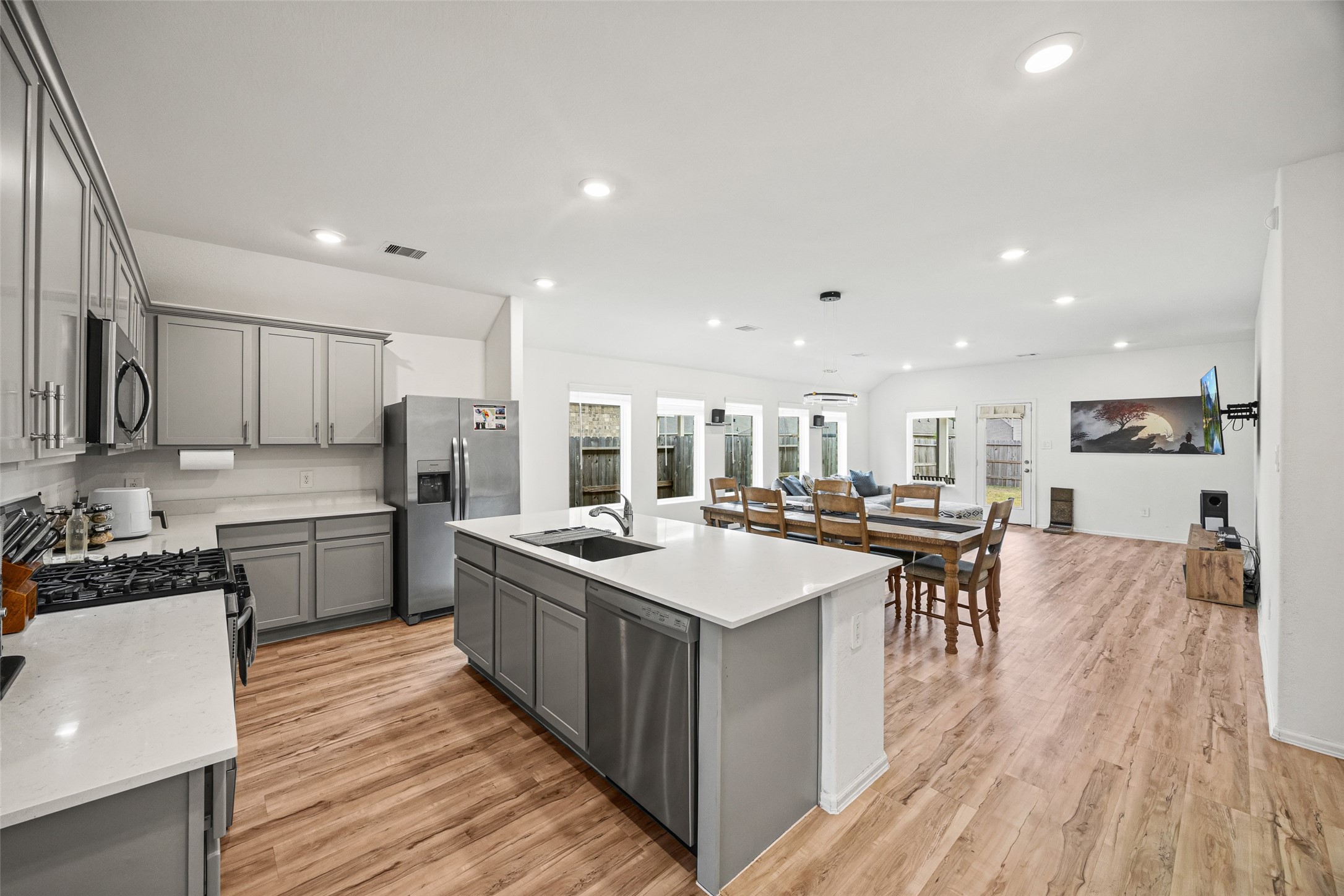 2822 Paradise Ridge Way Conroe, TX 77301 - Photo 10 of 21 a kitchen with stainless steel appliances a stove top oven a sink a refrigerator and white cabinets with wooden floor