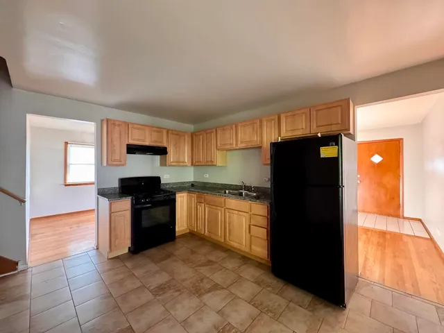 a kitchen with granite countertop a refrigerator and a stove top oven