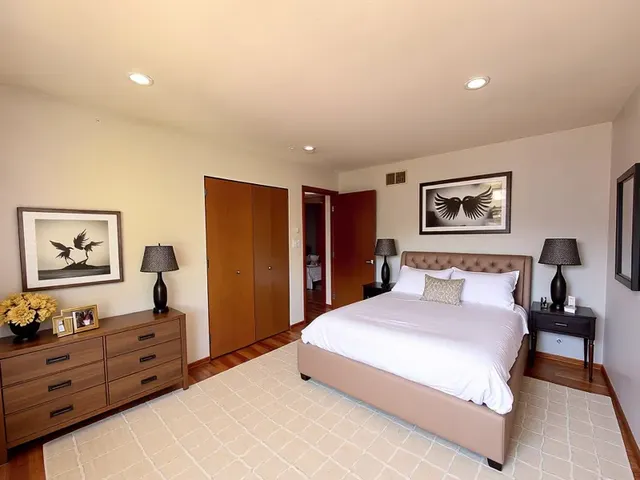 a spacious bedroom with a large bed and a painting on the wall