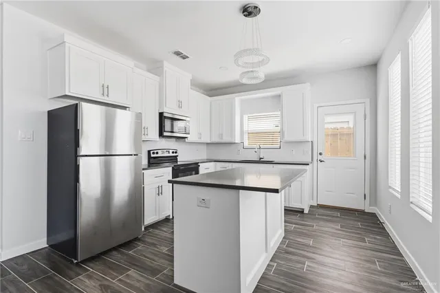 a kitchen with stainless steel appliances granite countertop a refrigerator a sink and a stove