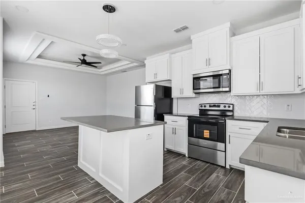 a kitchen with granite countertop a stove top oven a sink dishwasher and a refrigerator with wooden floor