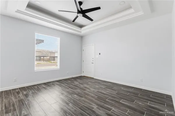 a view of empty room with wooden floor and fan