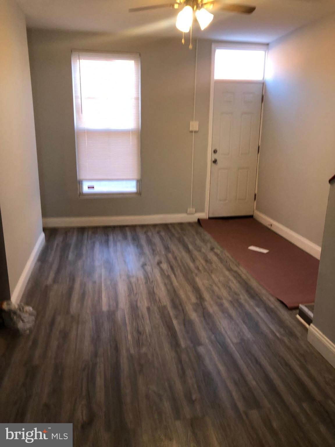 2123 East Chase Street Baltimore, MD 21213 - Photo 2 of 21 an empty room with wooden floor and windows