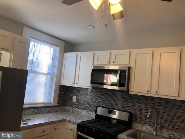 a kitchen with granite countertop a refrigerator a stove a microwave and cabinets