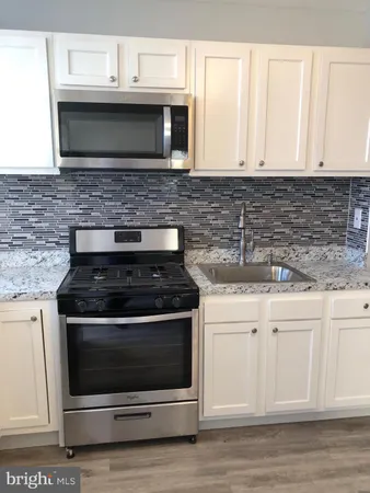 a kitchen with granite countertop white cabinets stainless steel appliances and a sink