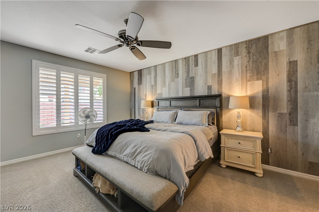 7049 Motley Road Las Vegas, NV 89178 - Photo 36 of 61 Textured wall paneling pairs with soft carpeting to create a cozy, modern bedroom retreat.