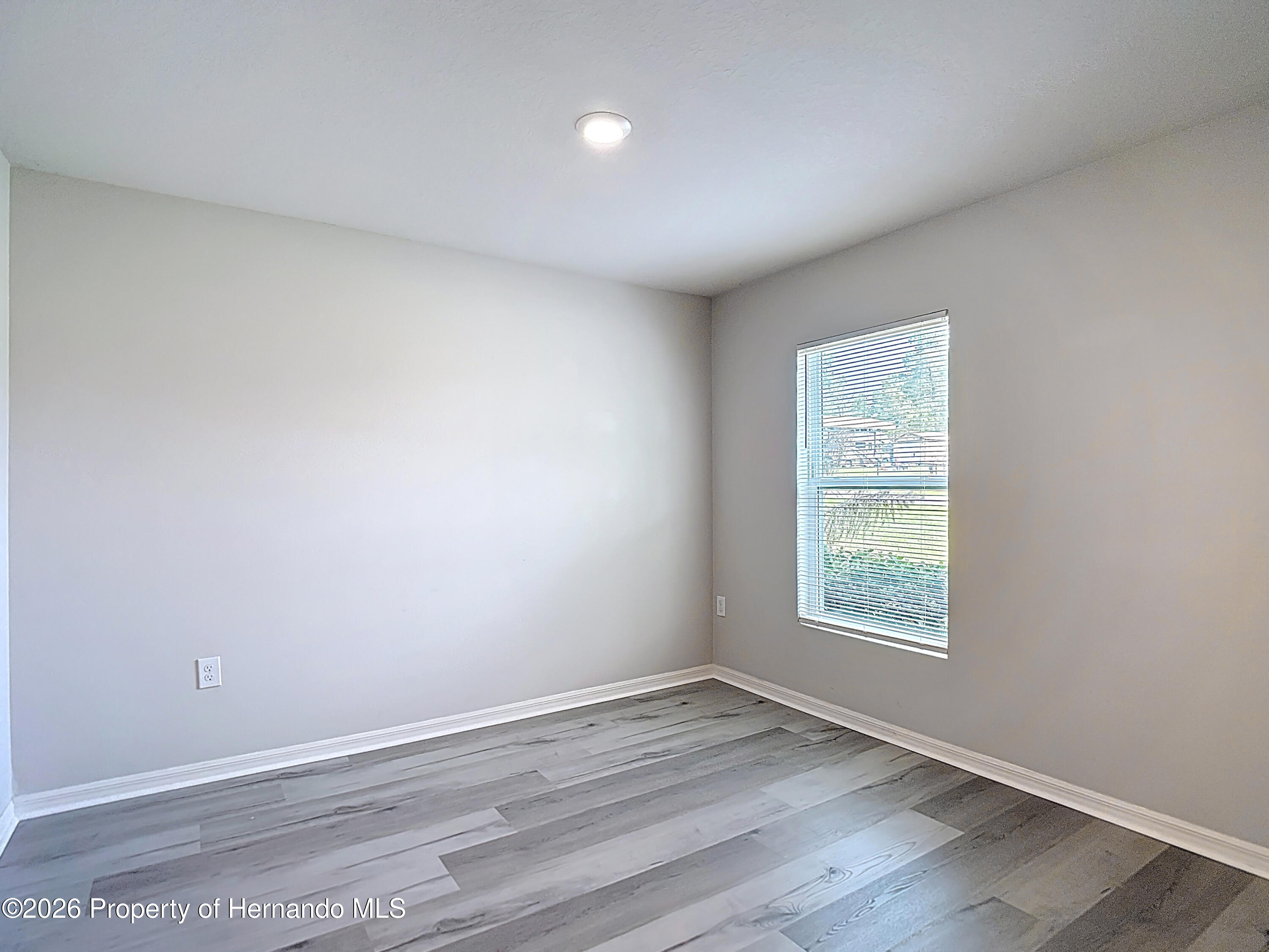 11374 Marcella Avenue Weeki Wachee, FL 34614 - Photo 13 of 70 an empty room with wooden floor and windows