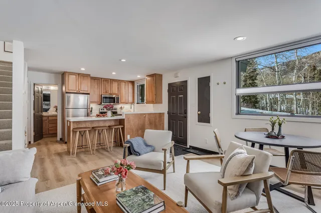 a living room with stainless steel appliances kitchen island granite countertop furniture and a large window