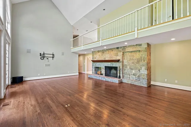 an empty room with wooden floor fireplace and windows