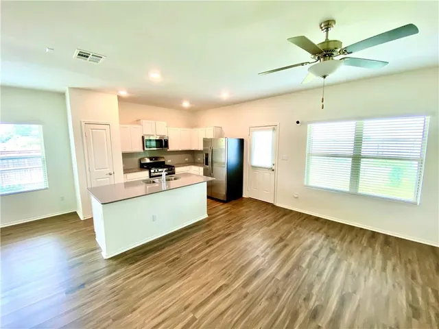 a kitchen with stainless steel appliances kitchen island hardwood floor and a window