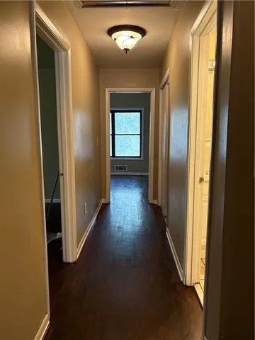 an empty room with wooden floor closet and windows